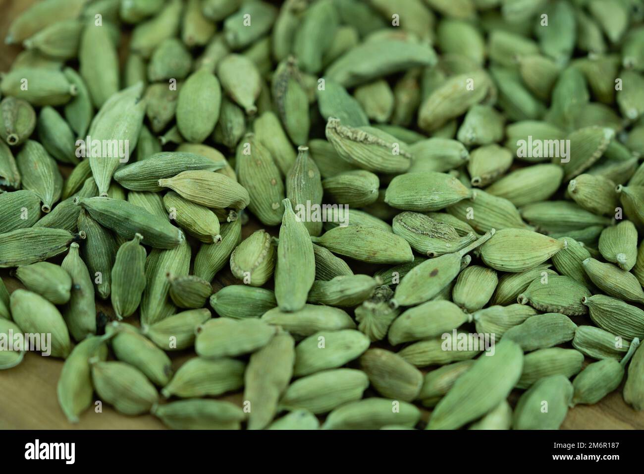 green cardamom Elettaria cardamomum on olive wood Stock Photo