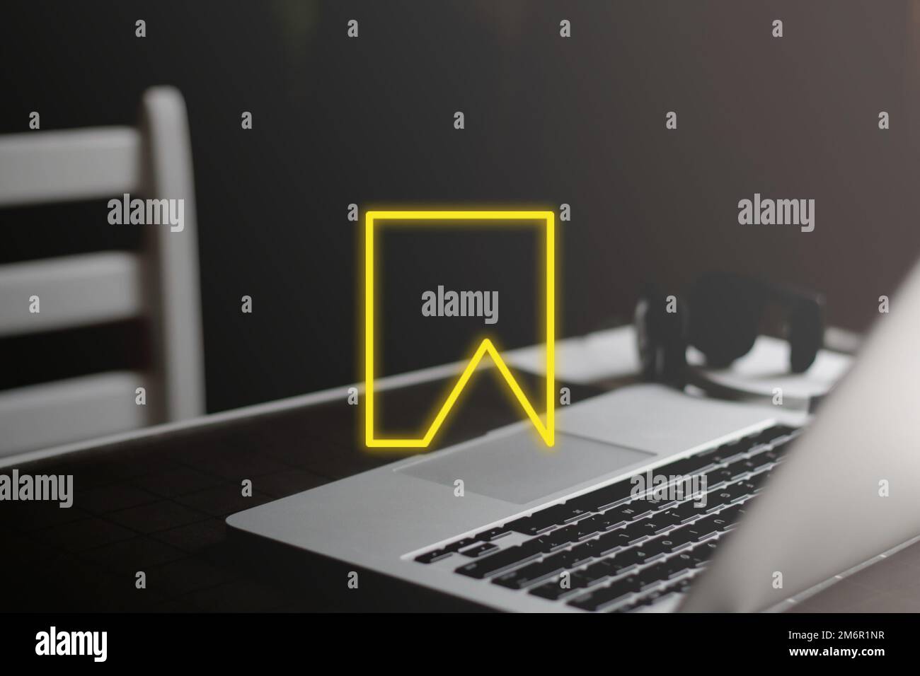Yellow bookmark icon on minimal workplace background. Save file on laptop Stock Photo