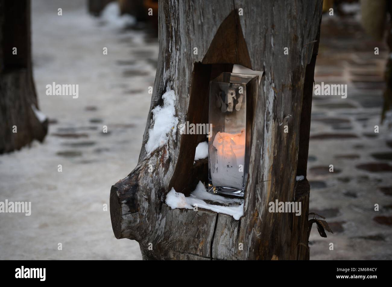 Country style outdoor lighting in a wooden log. Candle inserted in a hollow log for outdoor lighting Stock Photo