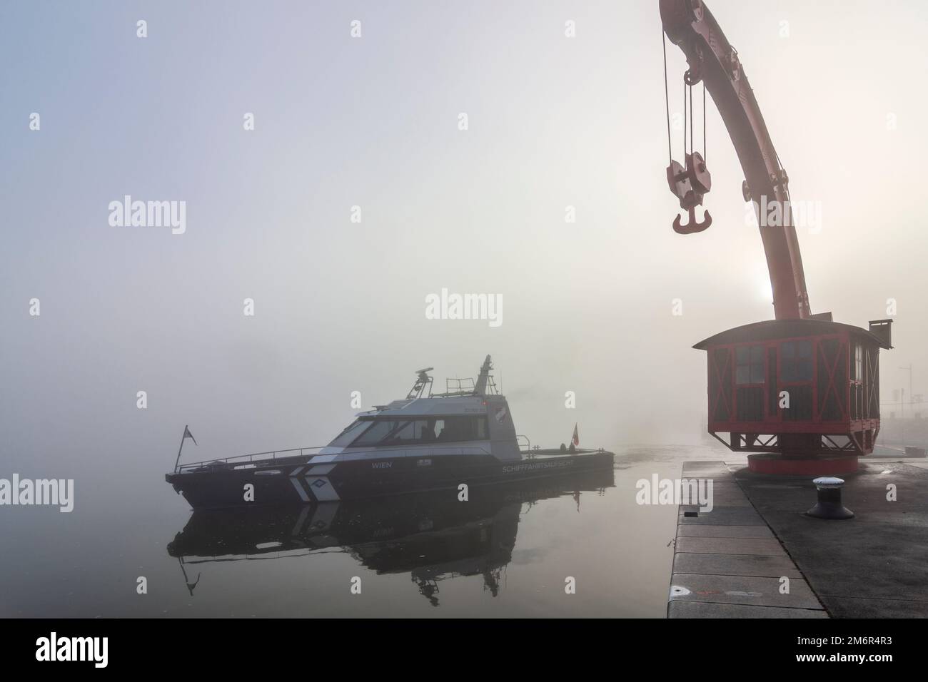 Wien, Vienna: mist at river Donau (Danube), old port crane, boat of Schifffahrtsaufsicht (Shipping Supervision) moves away in 02. Leopodstadt, Wien, A Stock Photo