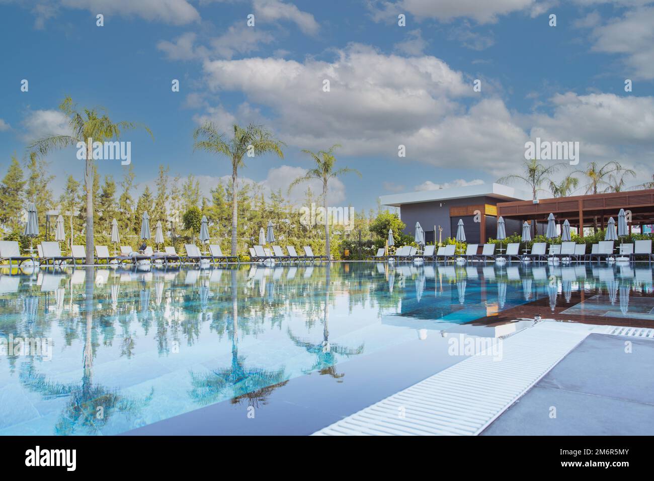 Beautiful luxury umbrella and chair around outdoor swimming pool in hotel and resort with coconut palm tree on blue sky Stock Photo