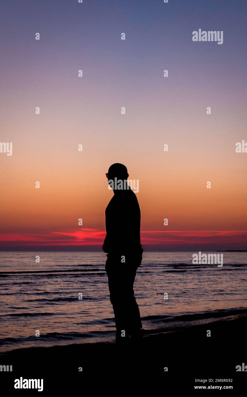Silhouette of a man on the beach at sunset Stock Photo - Alamy