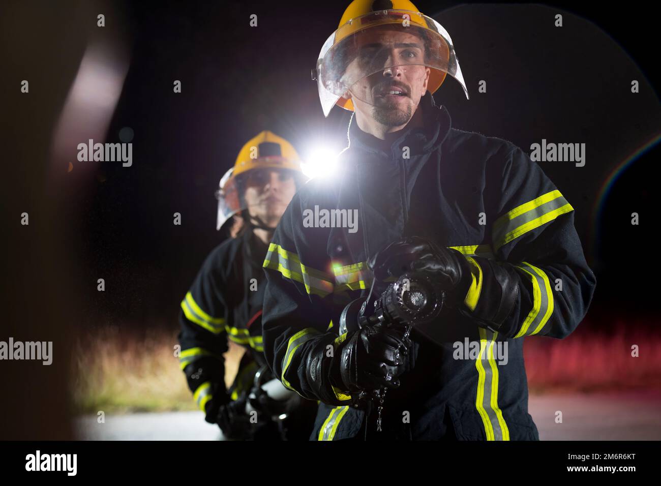 Firefighters using a water hose to eliminate a fire hazard. Team of