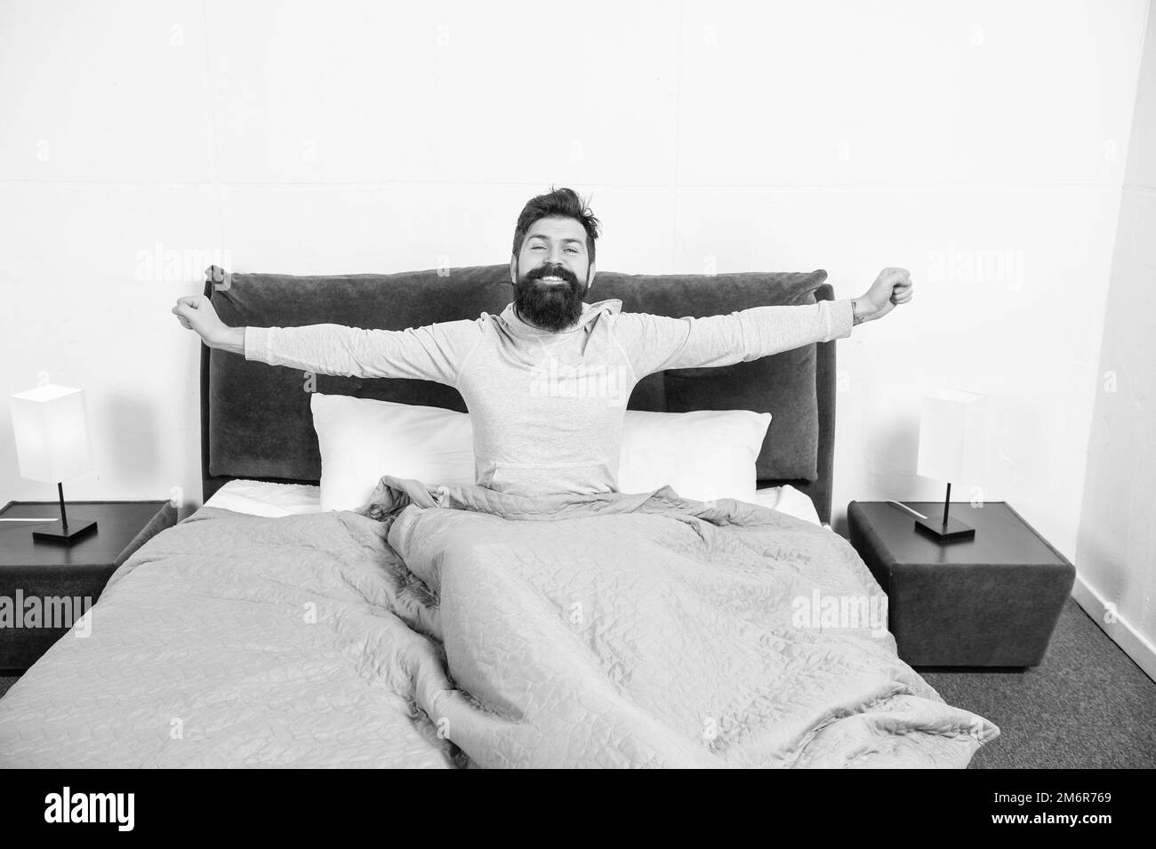 Happy guy smiling and stretching in bed waking up after sleep, morning Stock Photo