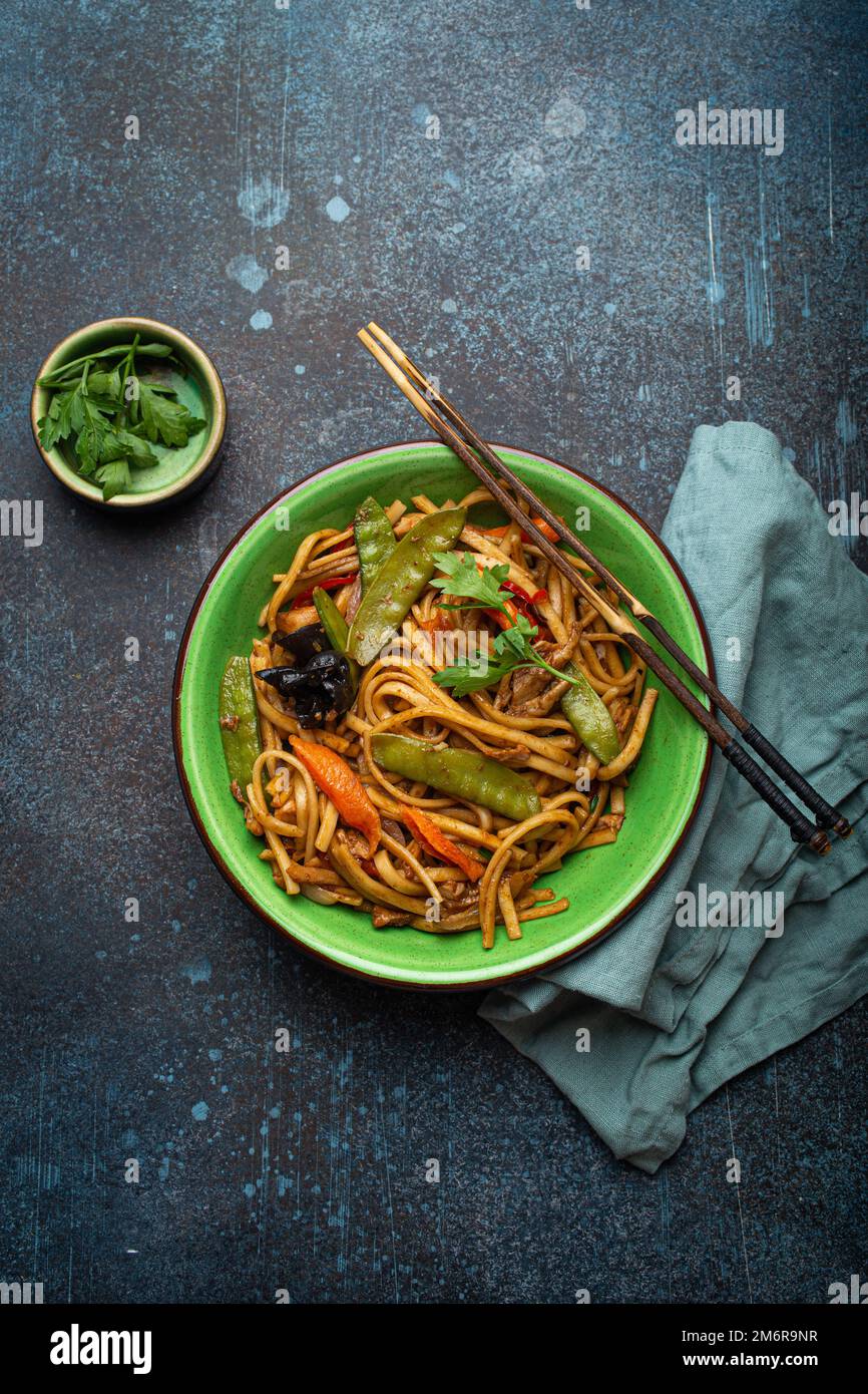 Asian Stir Fry Noodles With Chicken And Veggies In Green Bowl Top View asian-stir-fry-noodles-with-chicken-and-veggies-in-green-bowl-top-view