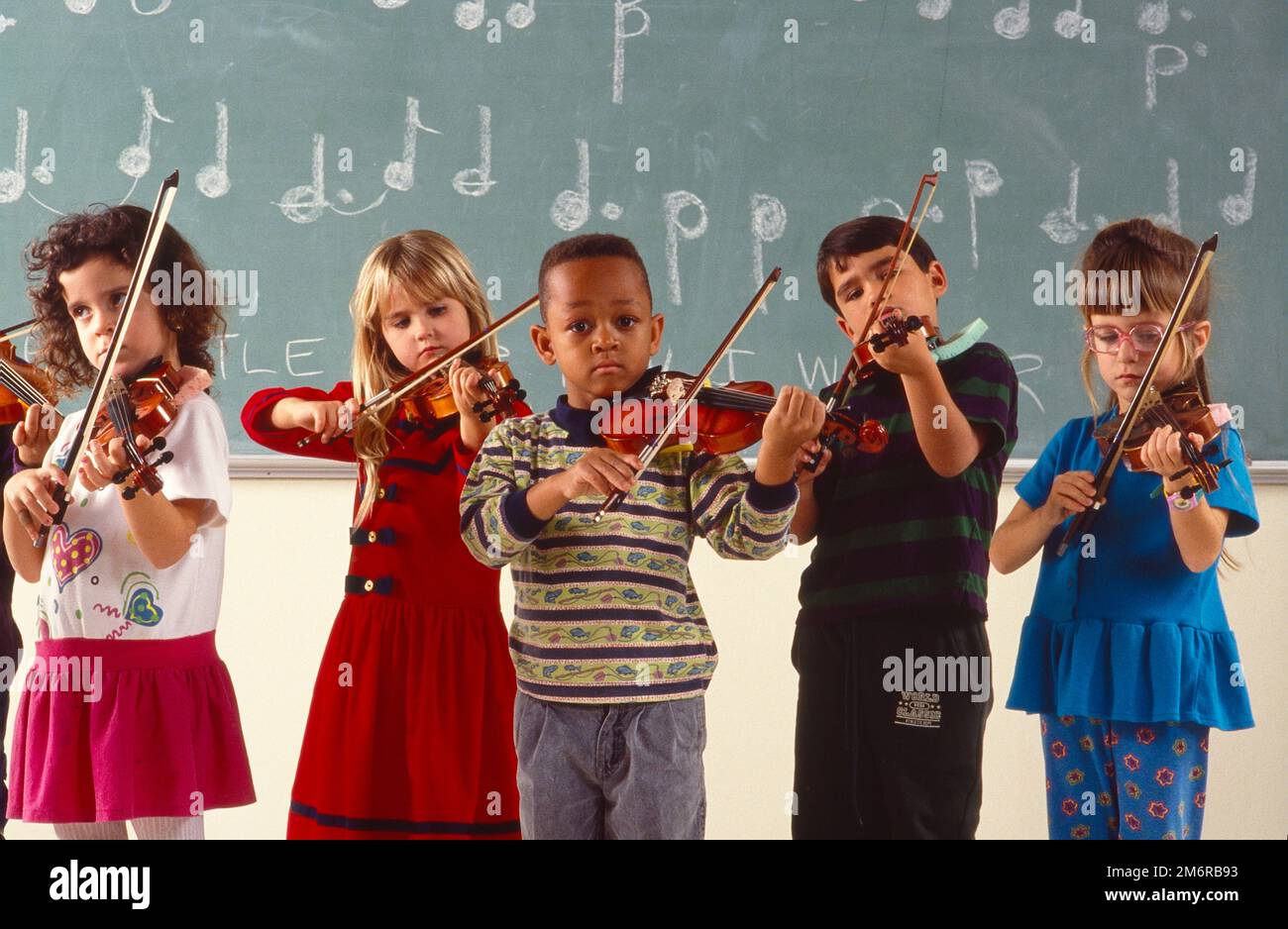 A group of young schoolage children, all playing violins in the