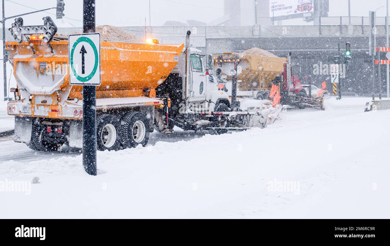 Snow plow truck in the city. Winter service vehicle. Snow removal on the road. Road snow removal. Truck putting salt. Two snowplows removing snow. Stock Photo