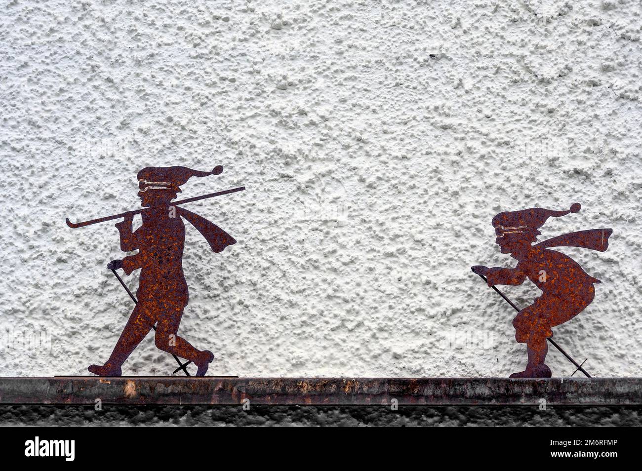 Zei iron rusty skiers in front of house wall, Hindelang, Allgaeu, Bavaria, Germany Stock Photo