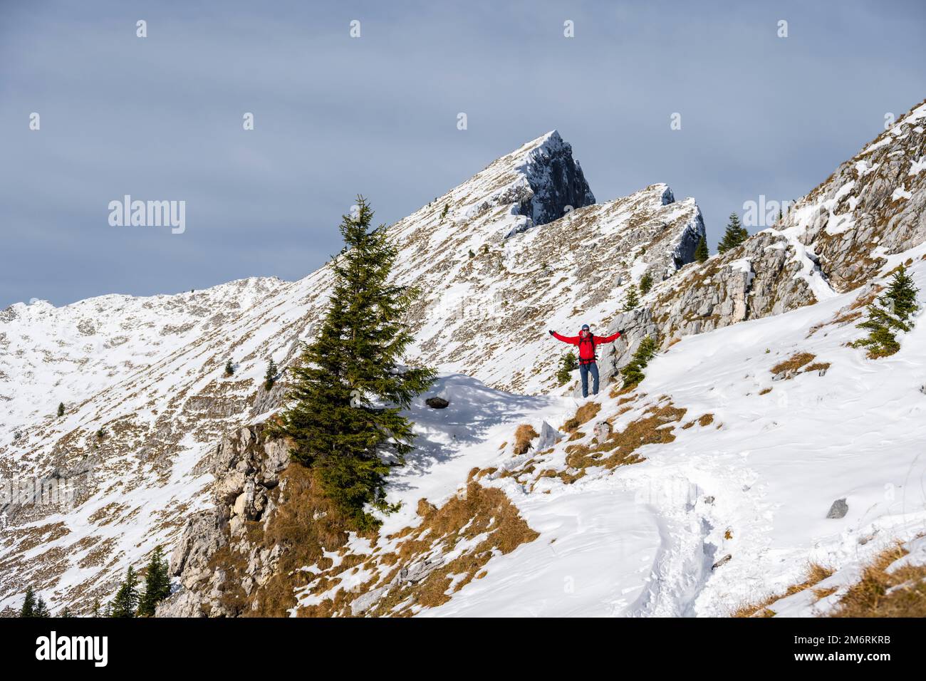 Happy hiker stretching his arms in the air, hiking trail in winter, path to Ammergauer Hochplatte, Ammergau Alps, Bavaria, Germany Stock Photo