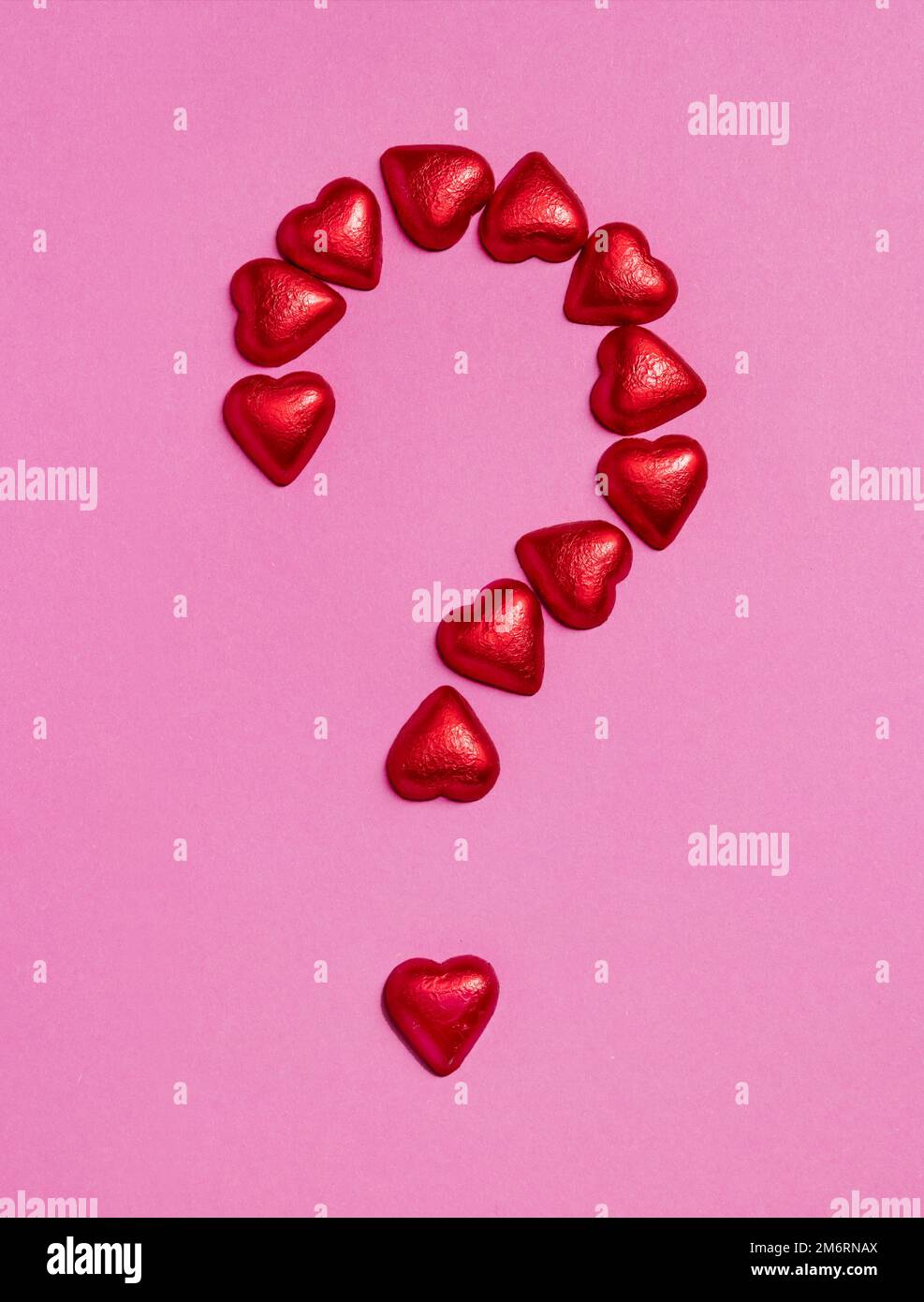 Be my Valentine? Bigger Question mark sign made of red chocolates hearts on pink background. Valentine's day. Holiday background Stock Photo