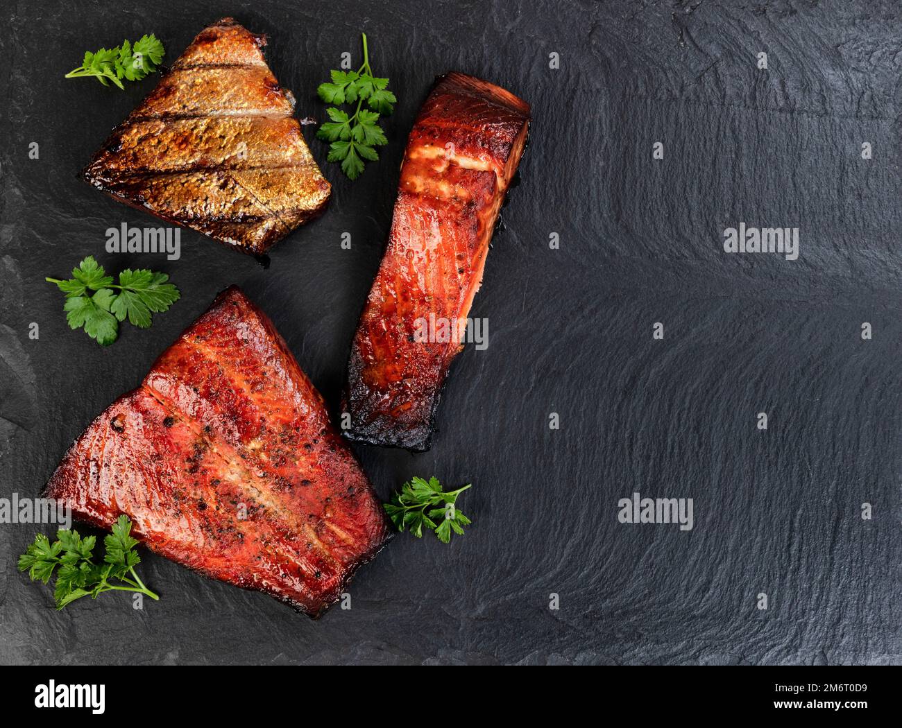 Freshly smoked fish, salmon trout, on a dark stone background. Flat lay view with copy space Stock Photo
