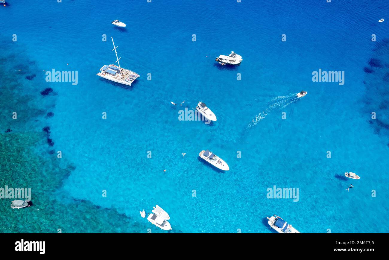 Drone aerial seascape with luxury yachts moored in the coast and unrecognised people swimming and relaxing. Summer vacations in Stock Photo