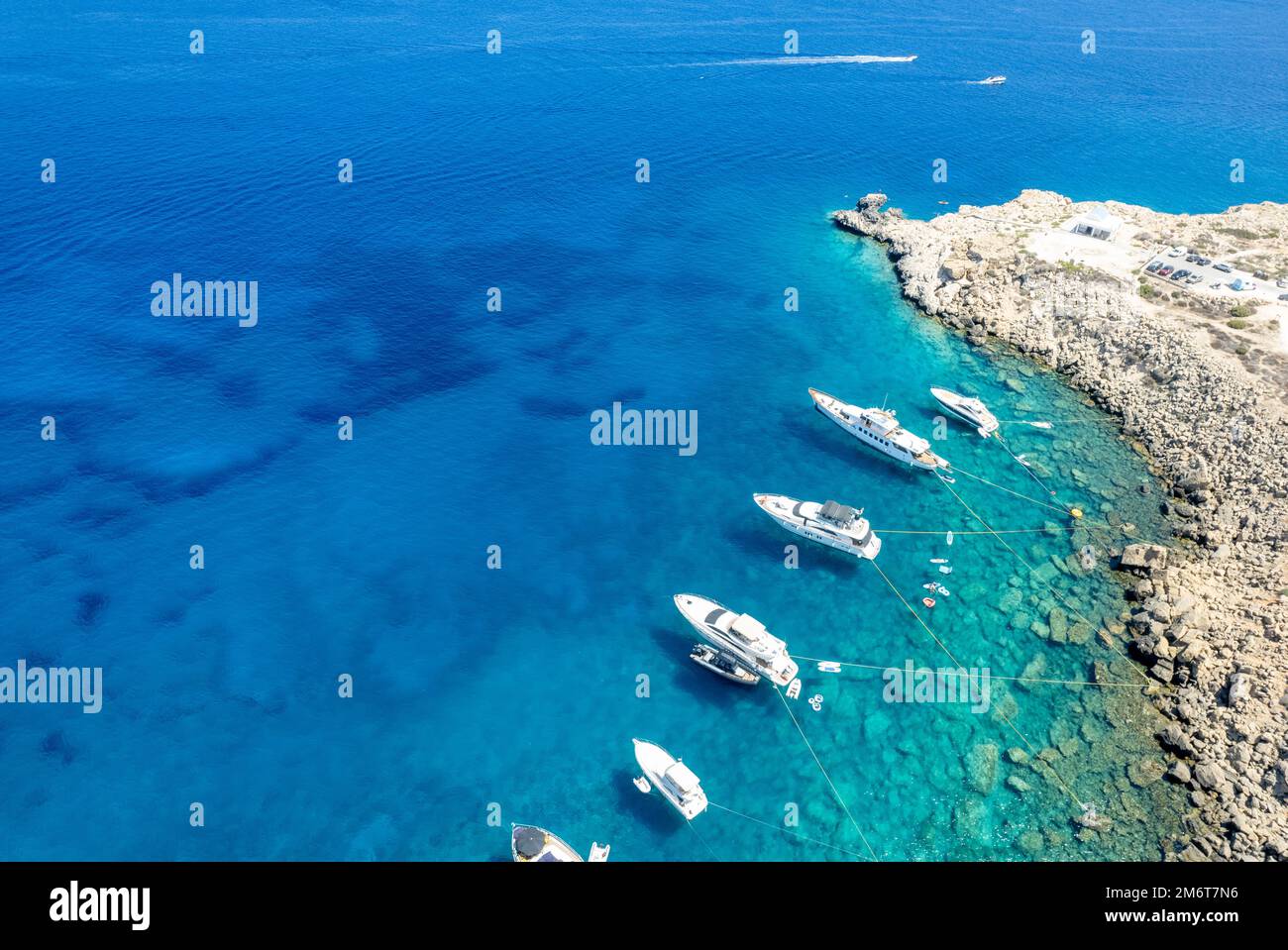 Drone aerial seascape with luxury yachts moored in the coast and unrecognised people swimming and relaxing. Summer vacations in Stock Photo