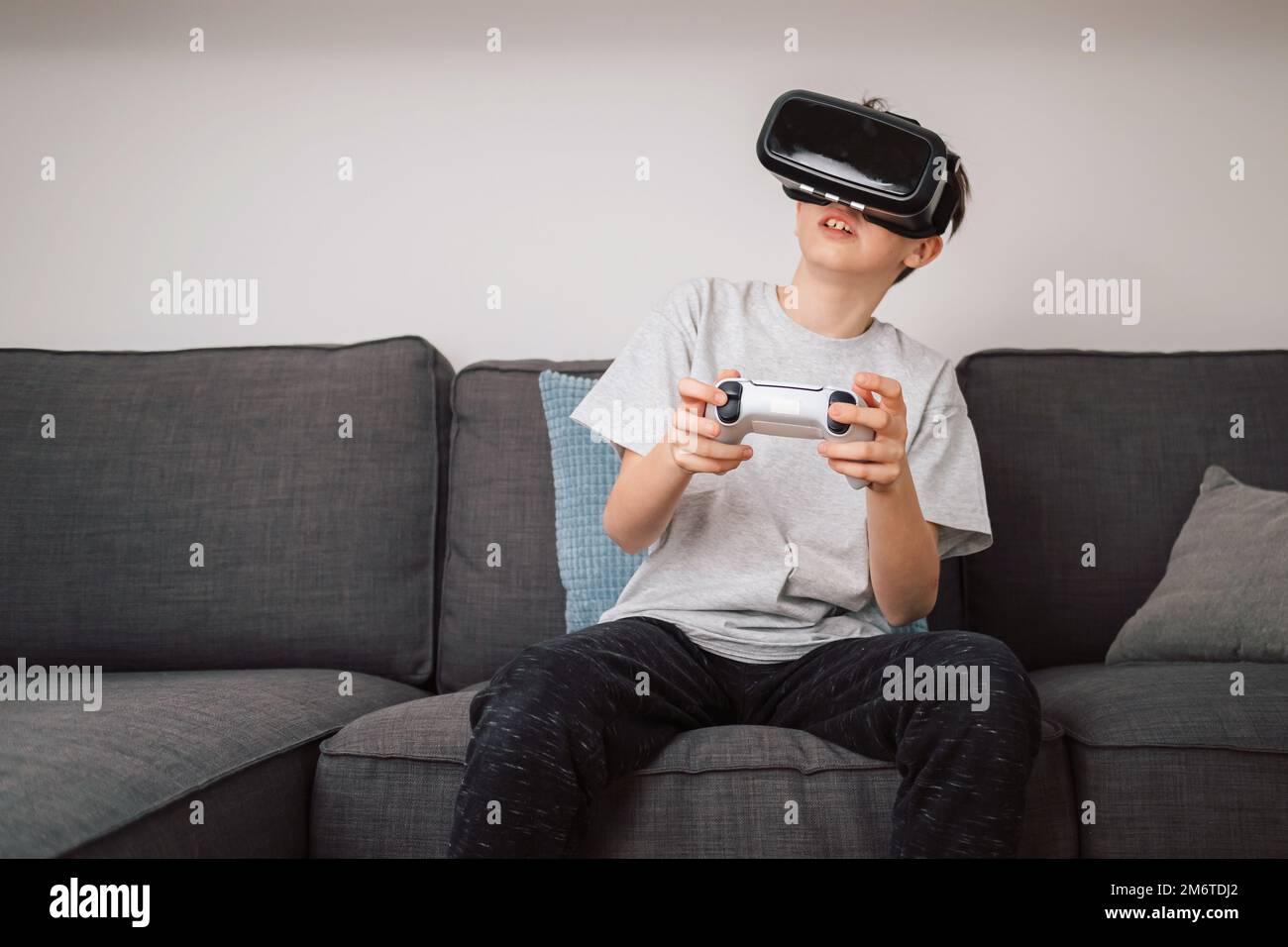 Boy having fun playing simulation games, using virtual reality headset and controller. Children and modern technology concept. Stock Photo