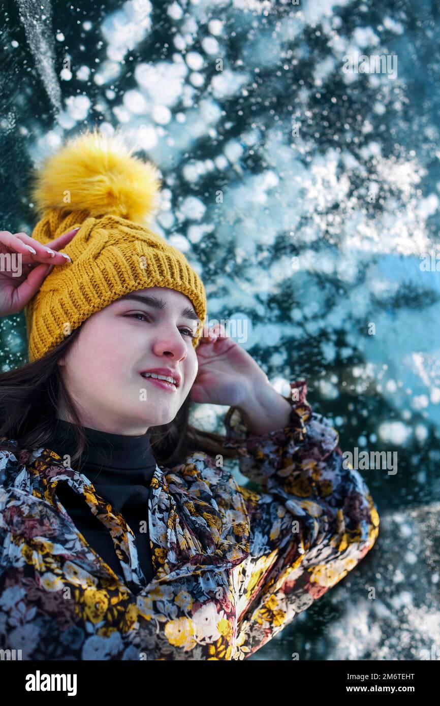 Fashionable image of a stunning woman posing on Baikal Lake ice wearing yellow hat Stock Photo