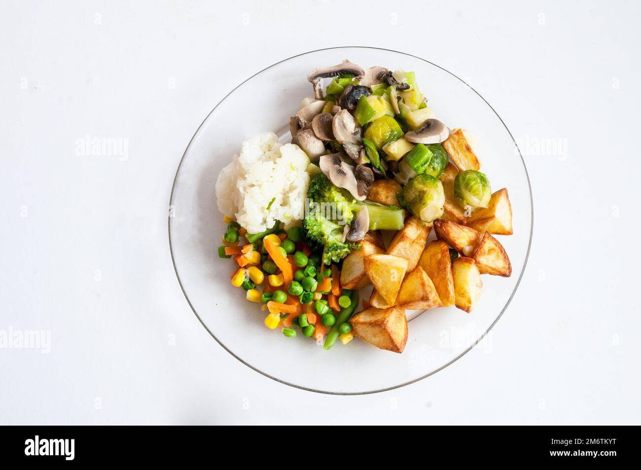 Cooked meal on a glass dinner plate a meat free vegetable meal of Cauliflower Brussel Sprouts Broccoli Mushrooms Mixed Vegetables and Roast Potatoes Stock Photo