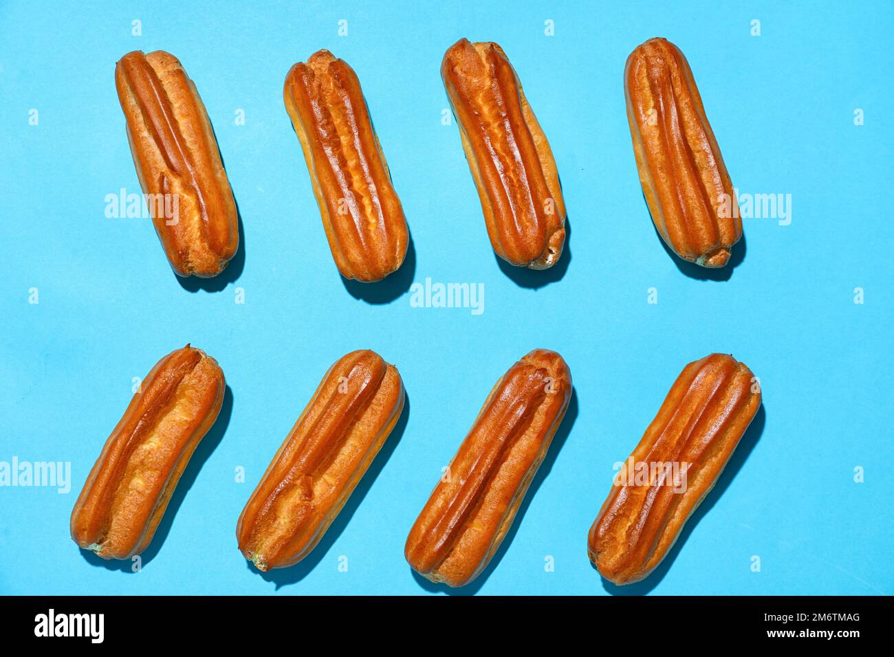 Composition with sweet eclairs on blue background Stock Photo