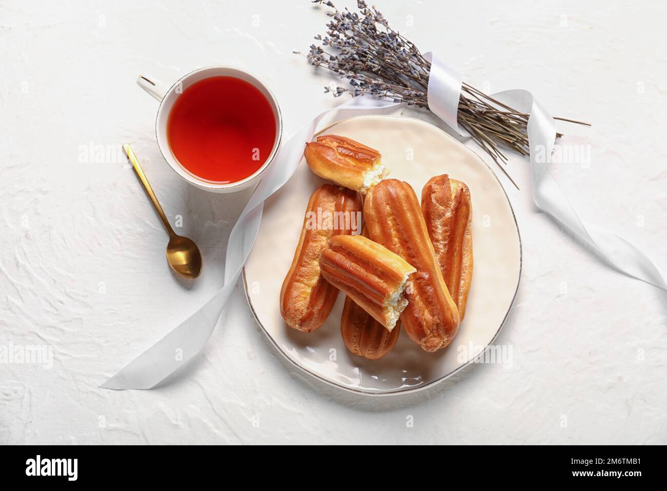 Composition with cup of tea, tasty eclairs and lavender on light background Stock Photo