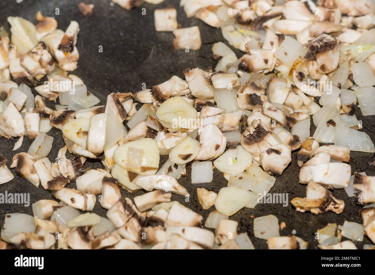 cooking chopped onion and mushrooms in a saucepan Stock Photo - Alamy