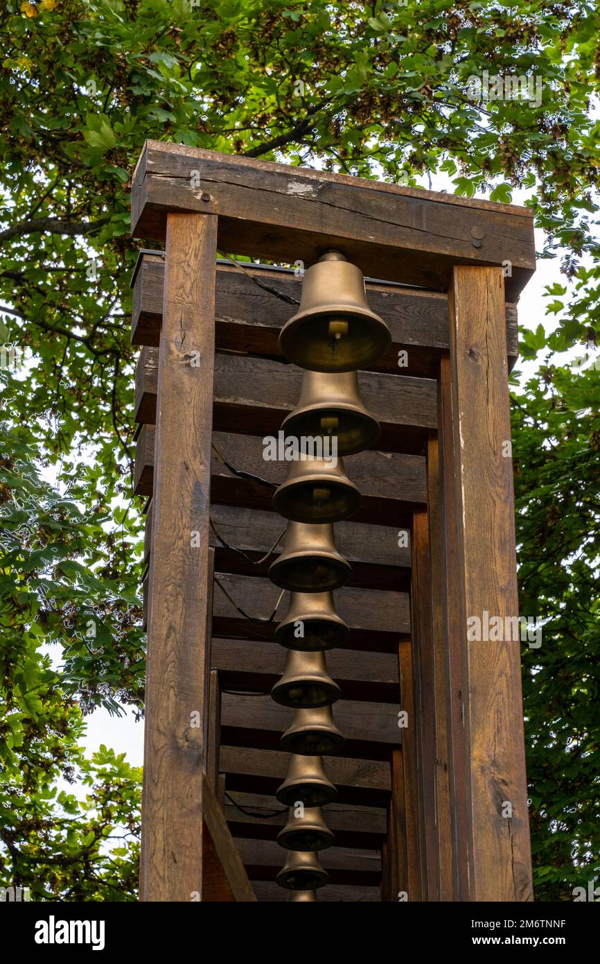 Wooden rack with many brass bells and trees behind Stock Photo - Alamy
