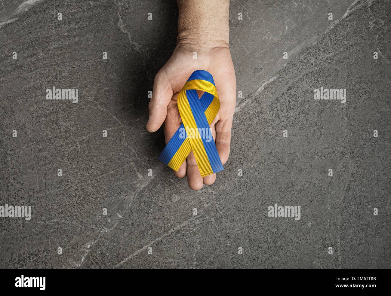 blue yellow ribbon lies on the male palm Stock Photo