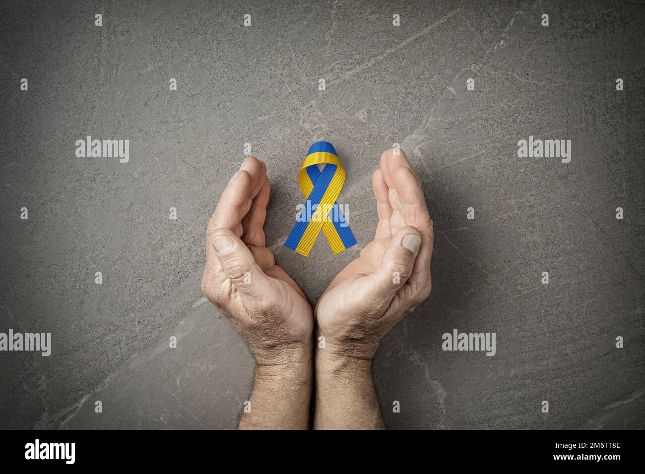 hands with blue and yellow ribbon on marble Stock Photo