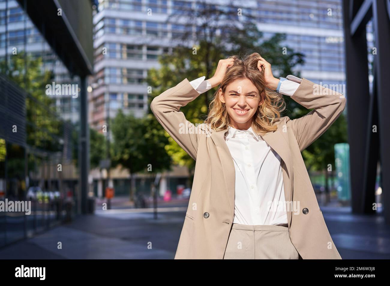 Stylish corporate woman, young lady boss in suit, looking confident and happy, posing outdoors on street Stock Photo