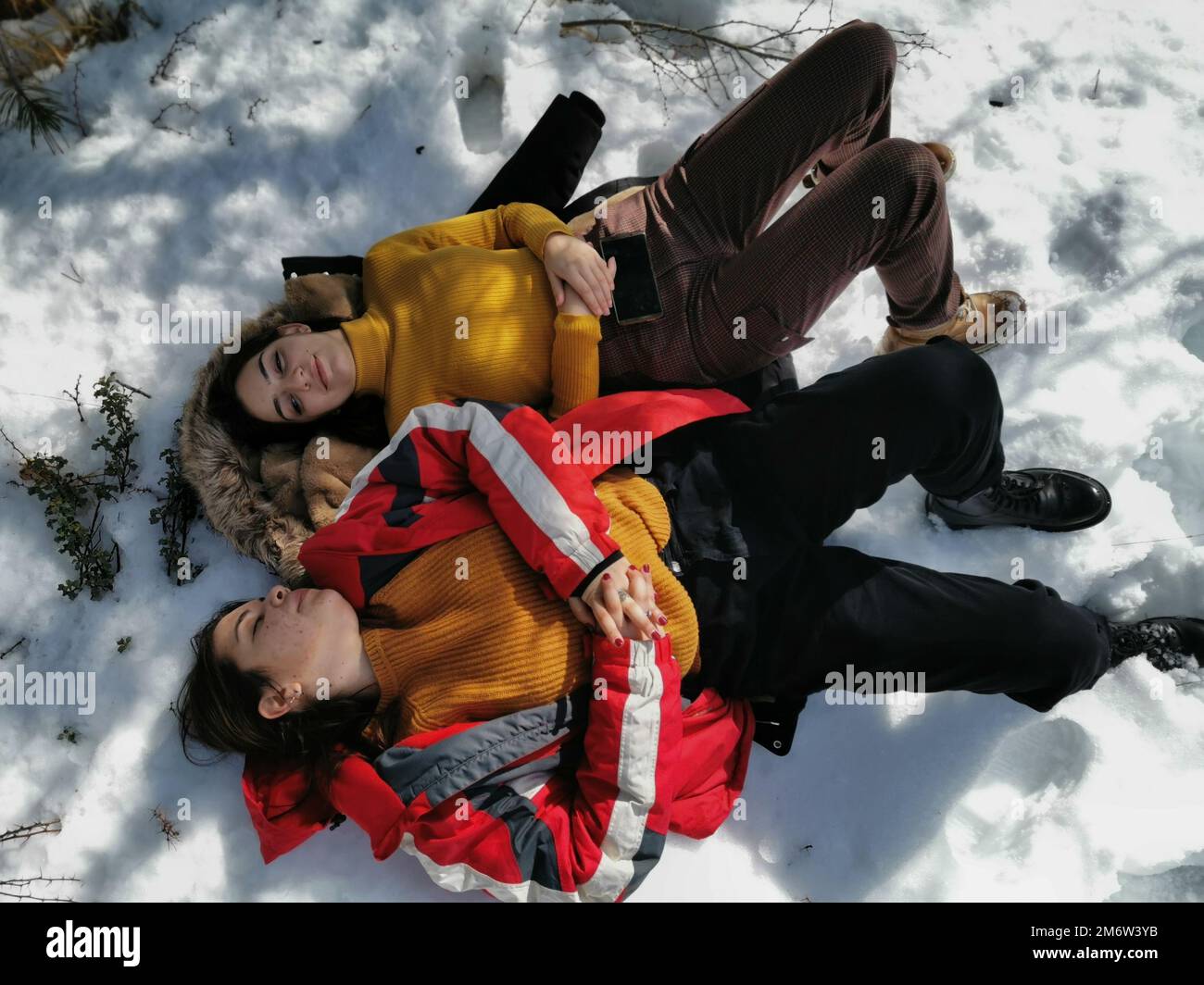 Young happy girls resting at snow in winter. Outdoor activity, healthy lifestyle Stock Photo
