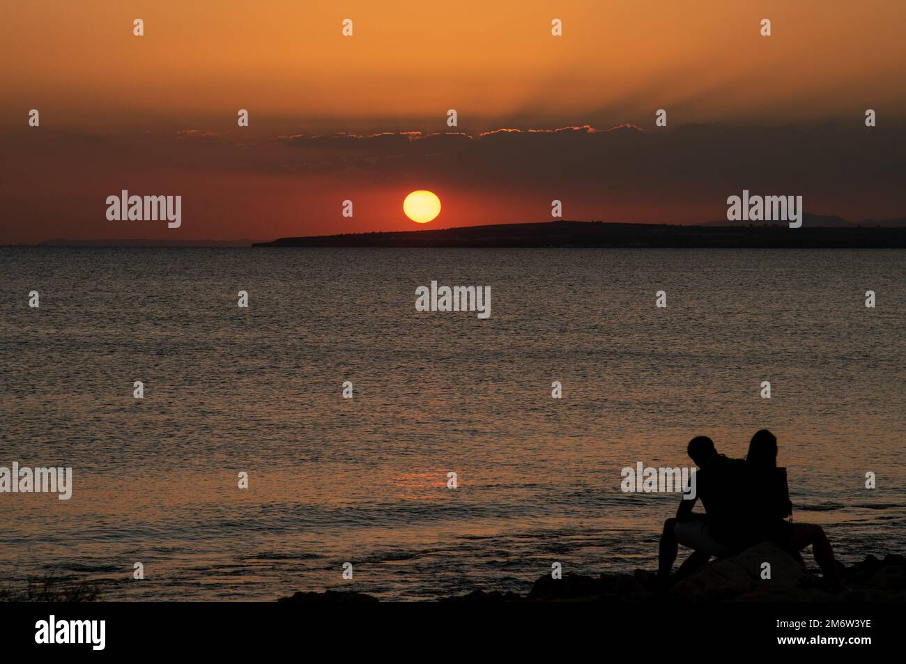 Silhouette of young couple enjoying beautiful sunset at the beach. Romantic moment human relationship Stock Photo