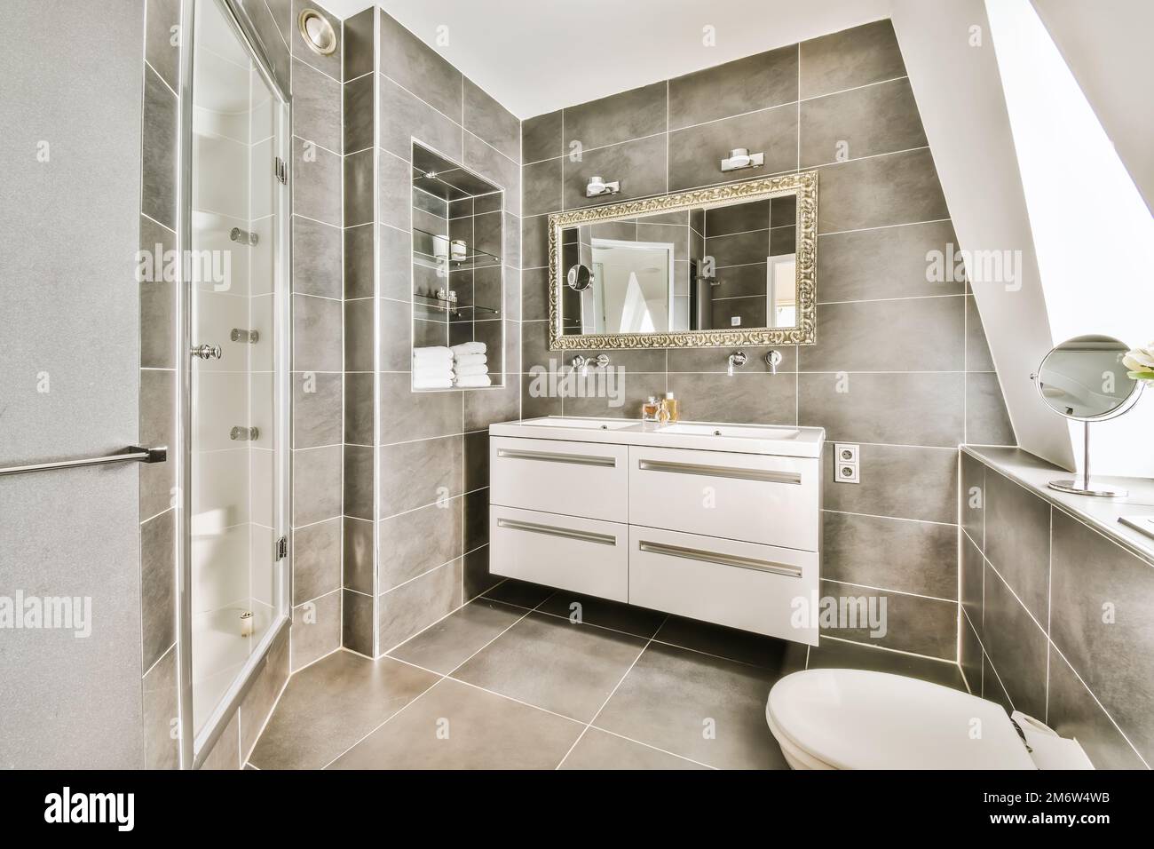 a modern bathroom with grey tile walls and white fixtures on the vanity ...