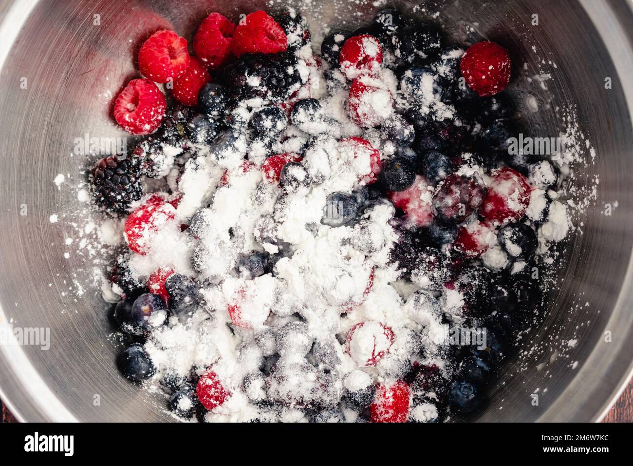 Mixed Berries Sprinkled with Cornstarch, Sugar, and Lemon Juice: Pie filling ingredients added to a mixing bowl full of fresh berries Stock Photo