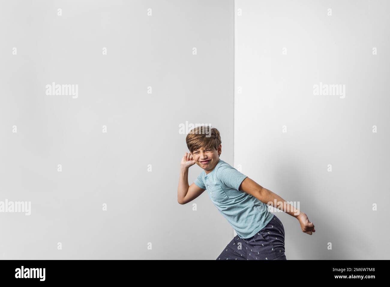 A pre-teen tween boy making a funny scrunched up face looking like he is about to take off and run Stock Photo