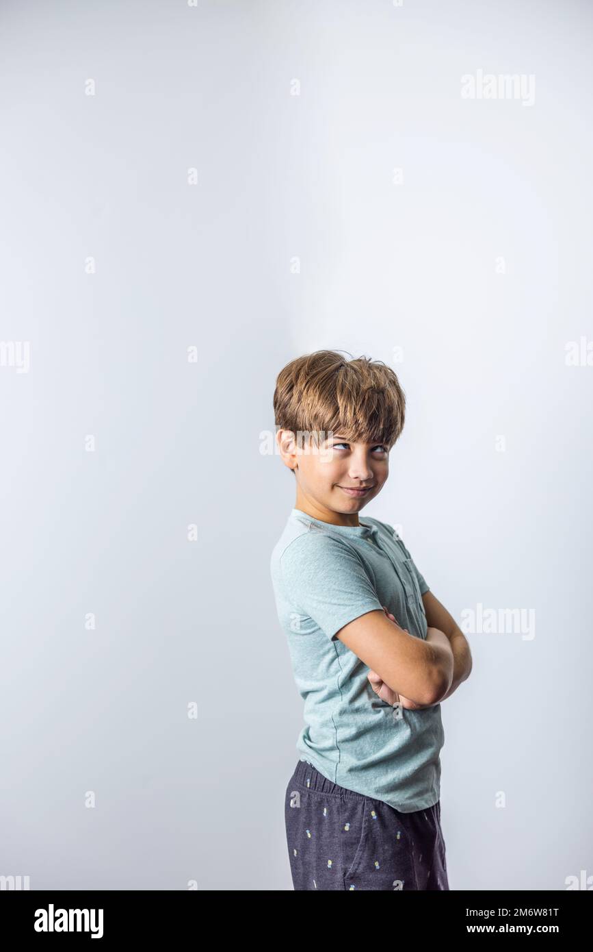 A pre-teen tween boy with his arms crossed with attitude standing near a corner with white walls with copy space Stock Photo