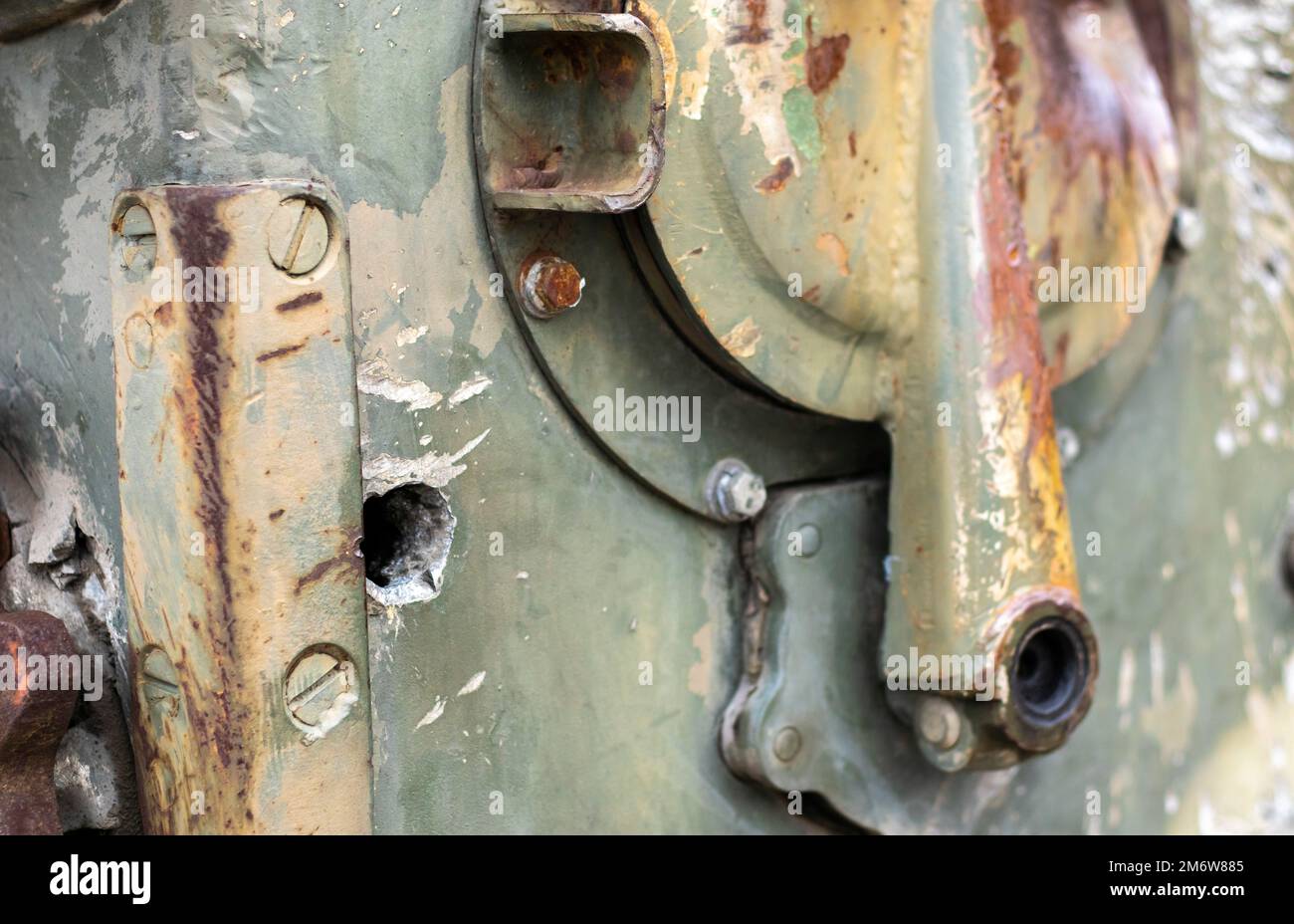 War in Ukraine, a hole in the armor of the BMP, pierced armor. Texture of green camouflage armored metal with damage and holes. Stock Photo
