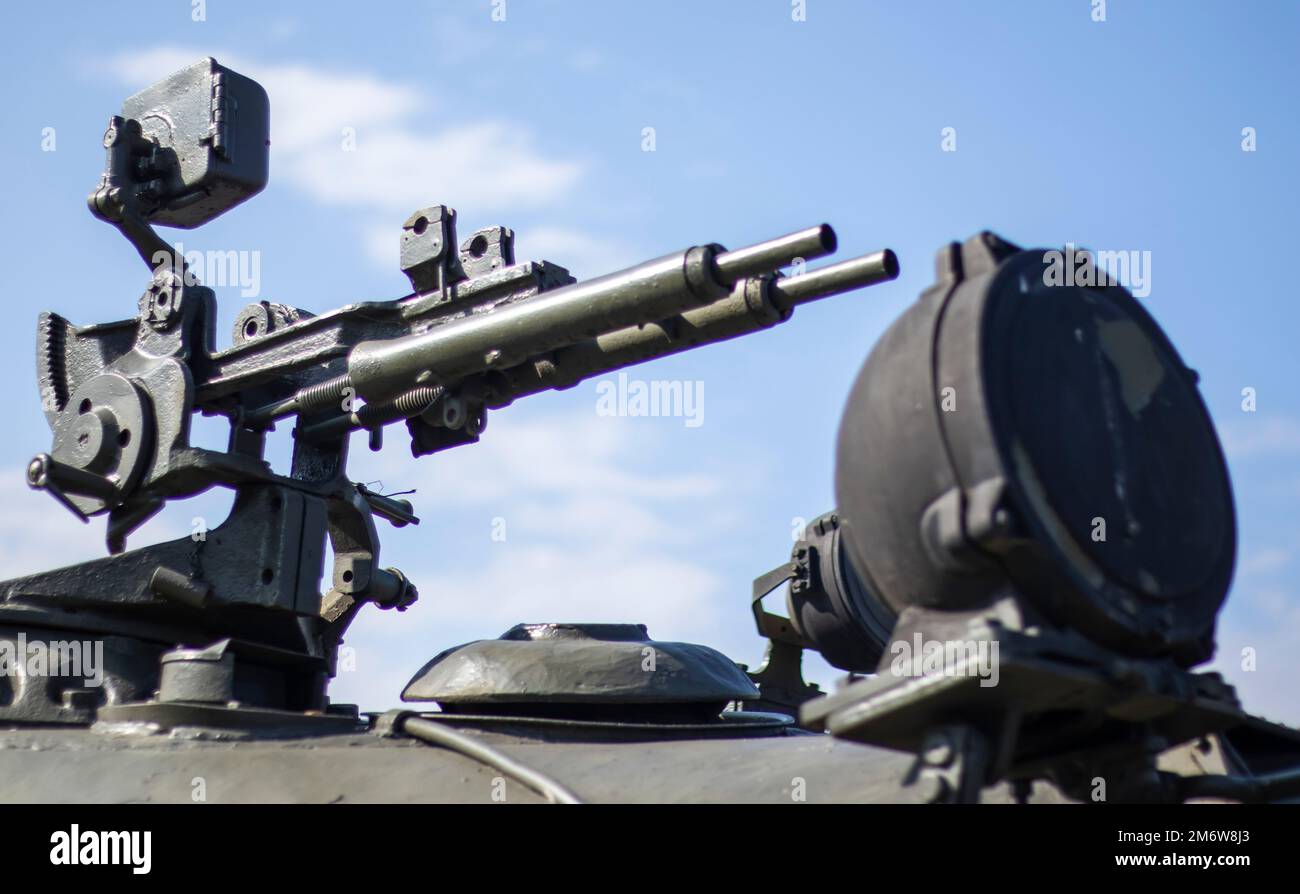 Machine gun on the turret of an armored personnel carrier. Heavy weapons of war, blue sky background. Army equipment for combat Stock Photo