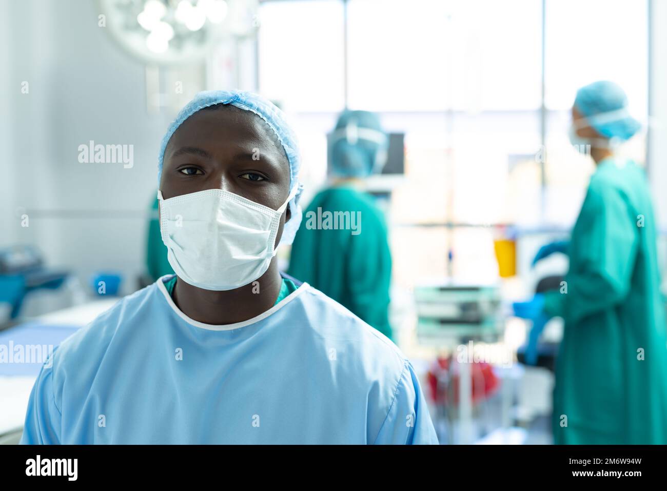 Portrait of african american male surgeon wearing face mask in ...