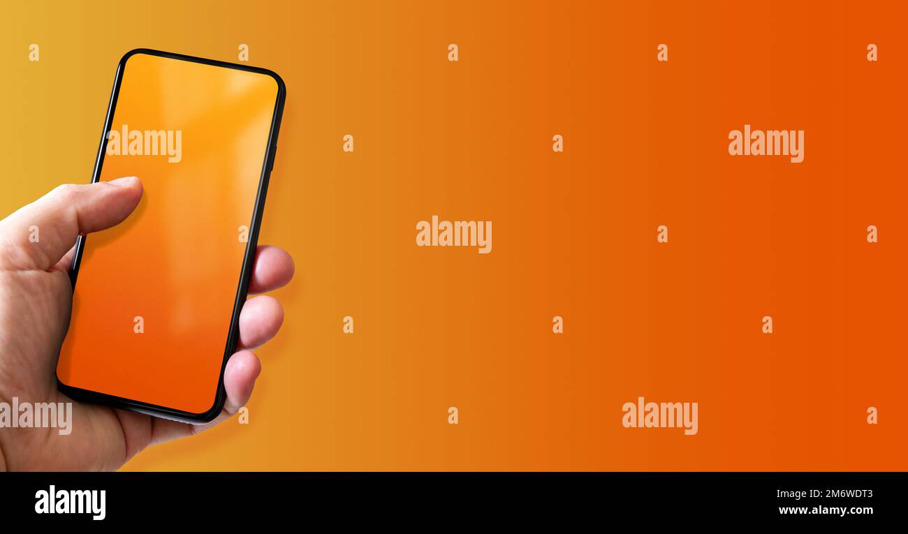 Hand holding a smartphone with blank orange screen. Colorful horizontal ...