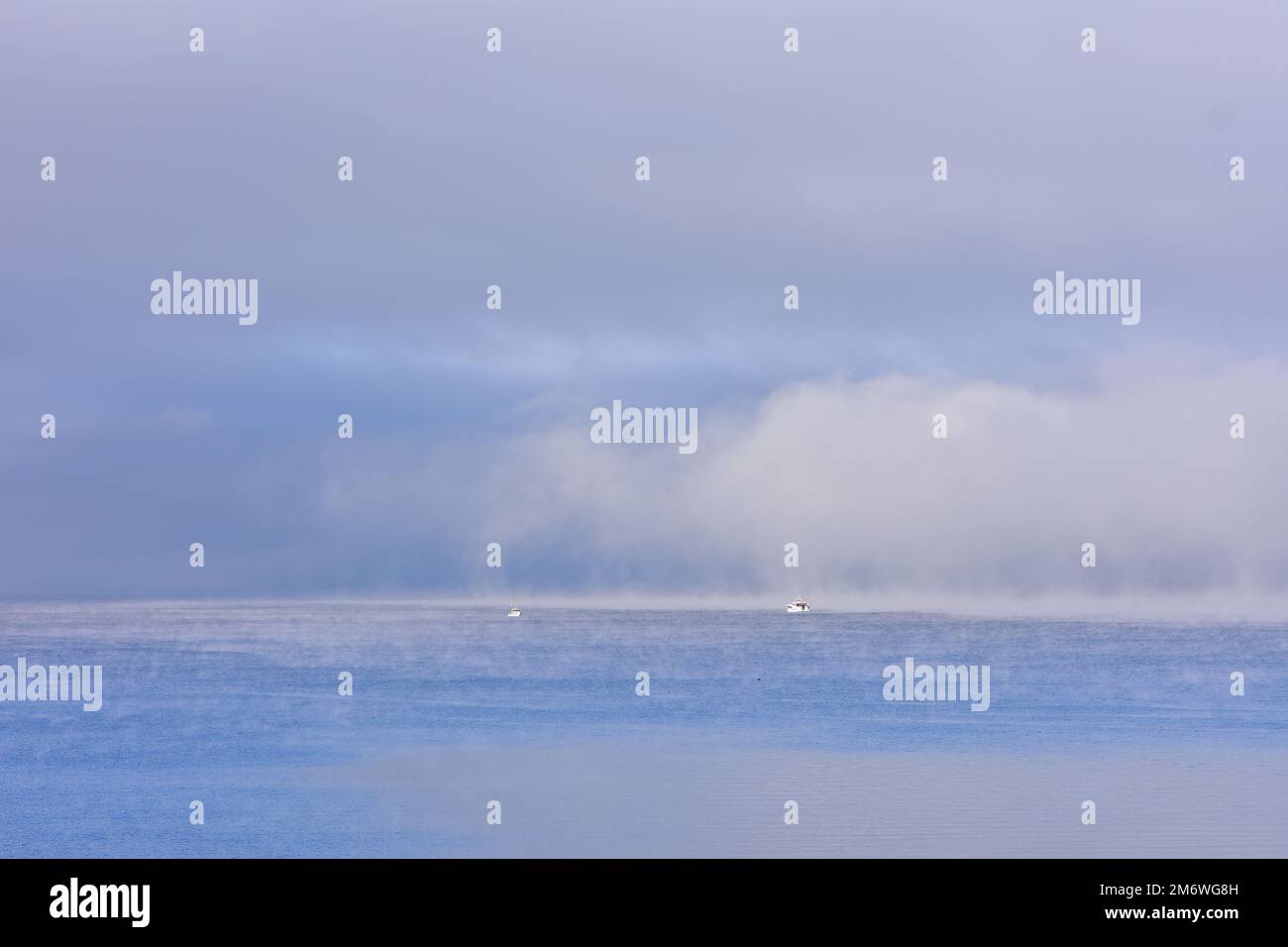 Boats at the edge of dense fog layer on Lake Taupo. Location: Taupo New Zealand Stock Photo
