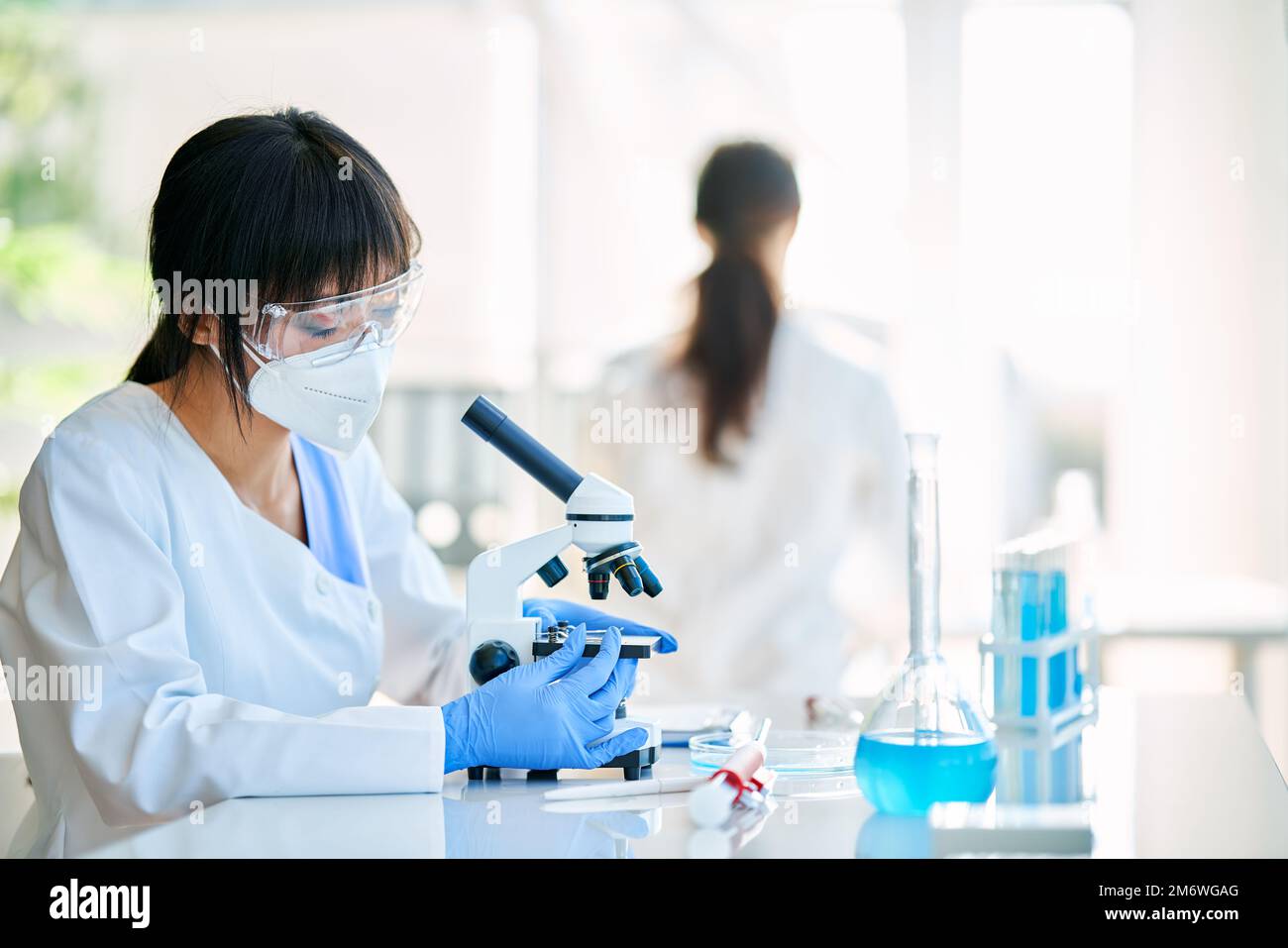 Asian scientist looking through a microscope working on medical research Stock Photo