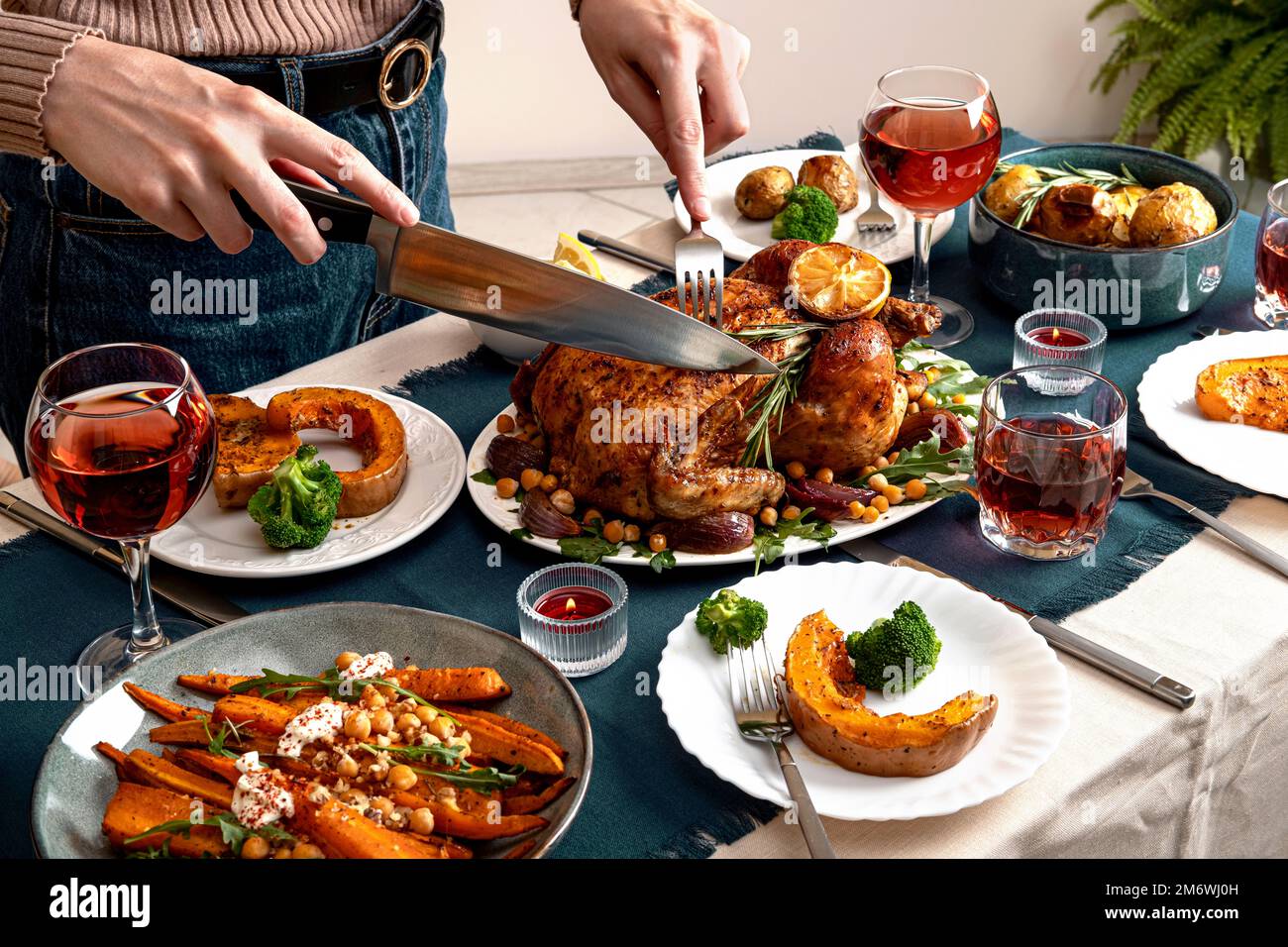 People celebrating Thanksgiving Day. Woman cutting meat for family and friends on table. Traditional holiday stuffed baked chick Stock Photo