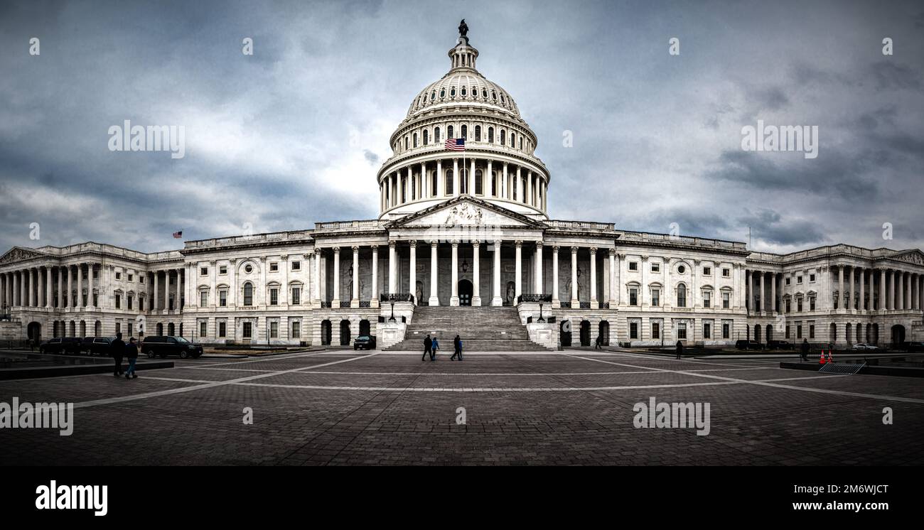Panoramic view of rear facade of Capitol building in Washington, D.C. on a cloudy and moody day. Some tourist passing in front of it. Stock Photo