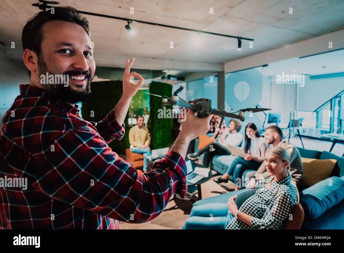 A bearded man in a modern office explaining to his young diverse team how a drone working Stock Photo