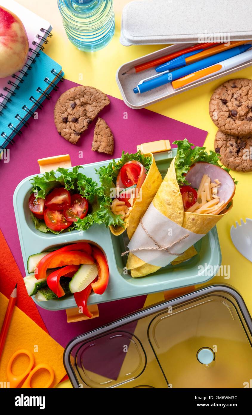 School lunch box with sandwich, vegetables, water, and fruits on table.  Healthy eating habits concept Stock Photo - Alamy