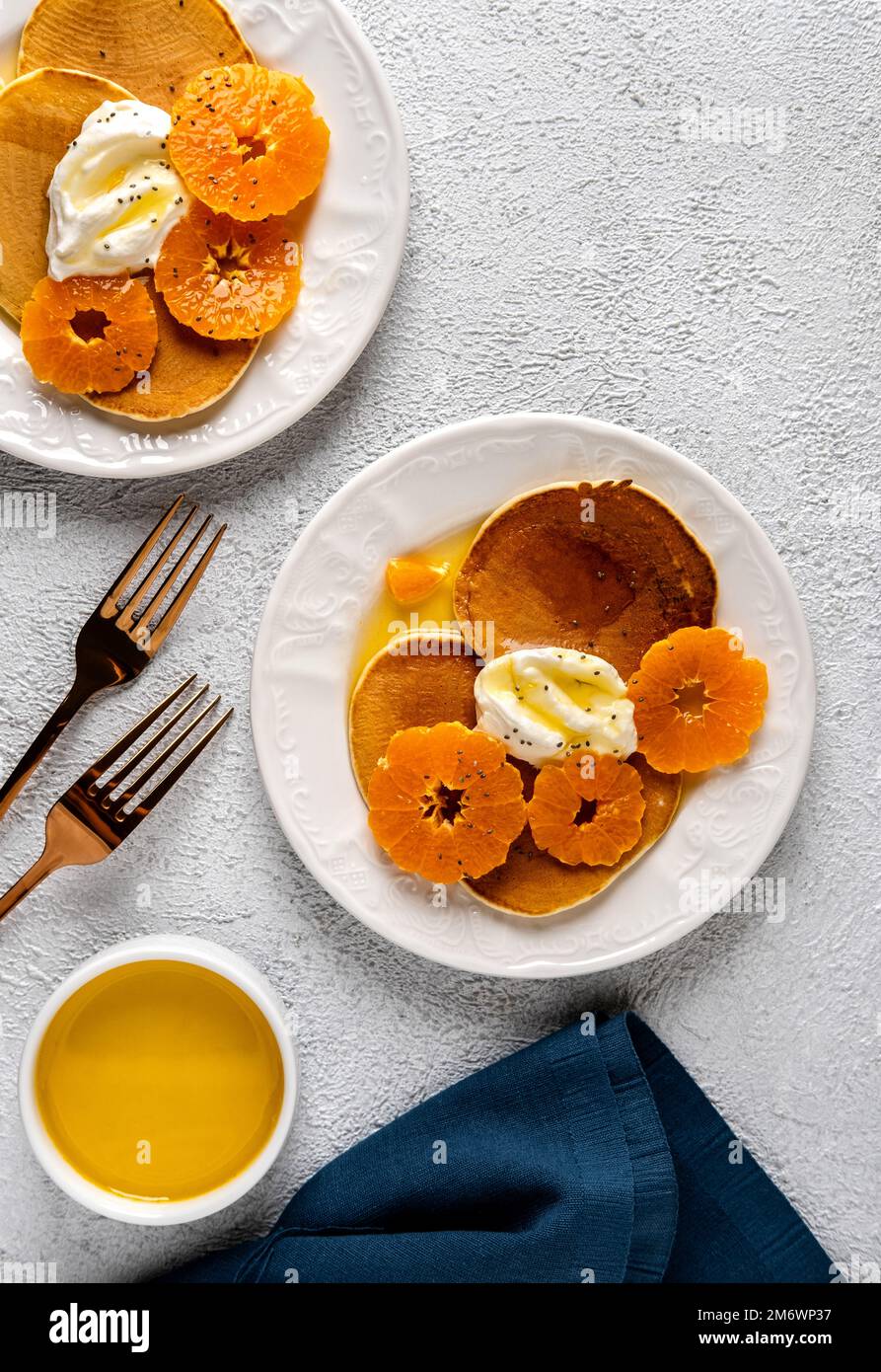 Delicious pancakes with tangerines and honey or maple syrup for breakfast on a light background. Copy space. Stock Photo