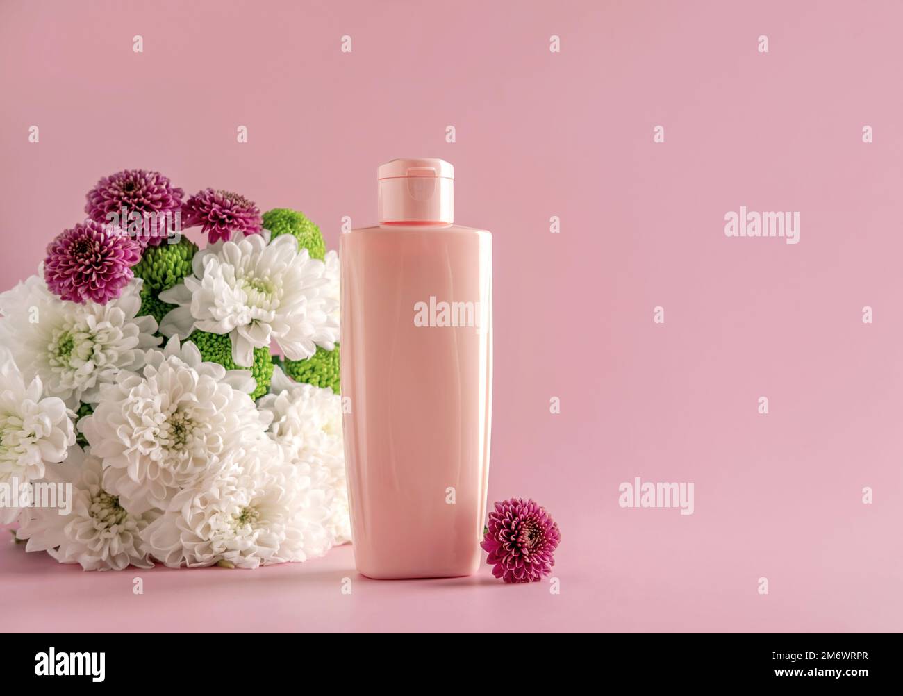 Mock up natural cosmetics: serum, cream, mask for advertising on light pink background with flowers. Organic products. Stock Photo
