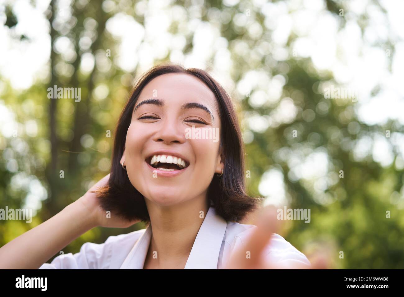 Genuine people. Portrait of asian woman laughing and smiling, walking in park, feeling joy and positivity Stock Photo