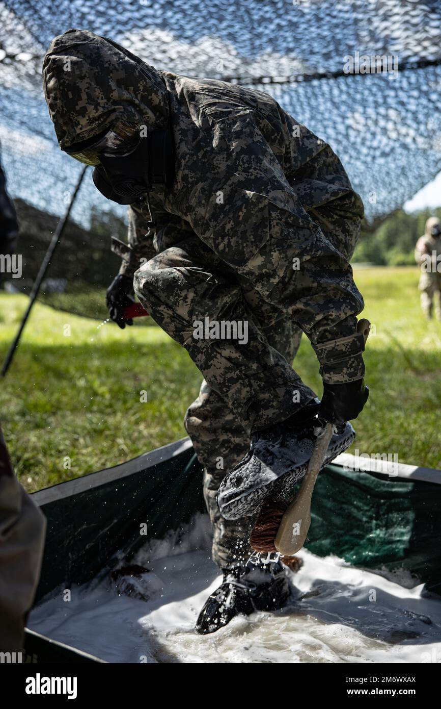 A U.S. Marine with Combat Logistics Regiment 27, 2nd Marine Logistics Group, washes boots with a general purpose decontaminate during Potomac Restore, a regimental exercise, at Camp Lejeune, North Carolina, May 7, 2022. This portion of Potomac Restore was utilized to enhance Marines’ and Sailors’ experience in recognizing and defending against simulated CBRN attacks. Stock Photo