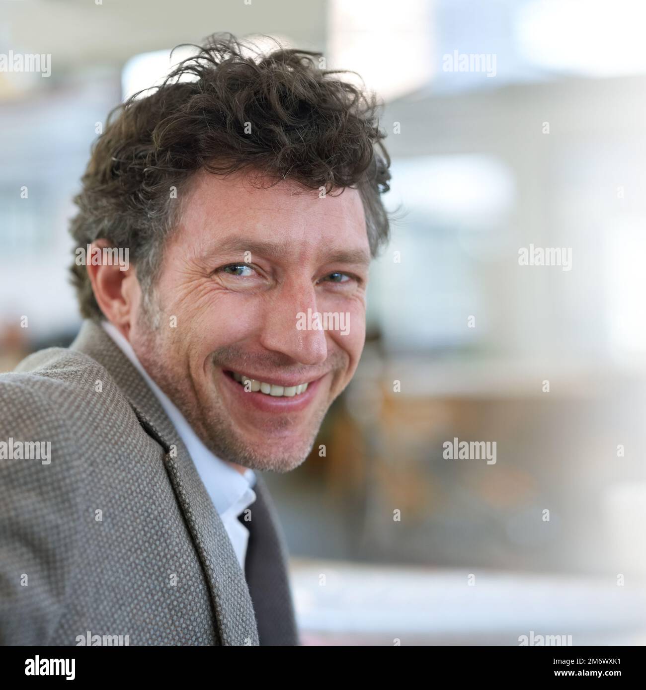 His career has him smiling. Portrait of a smiling businessman seated at his desk in an office. Stock Photo