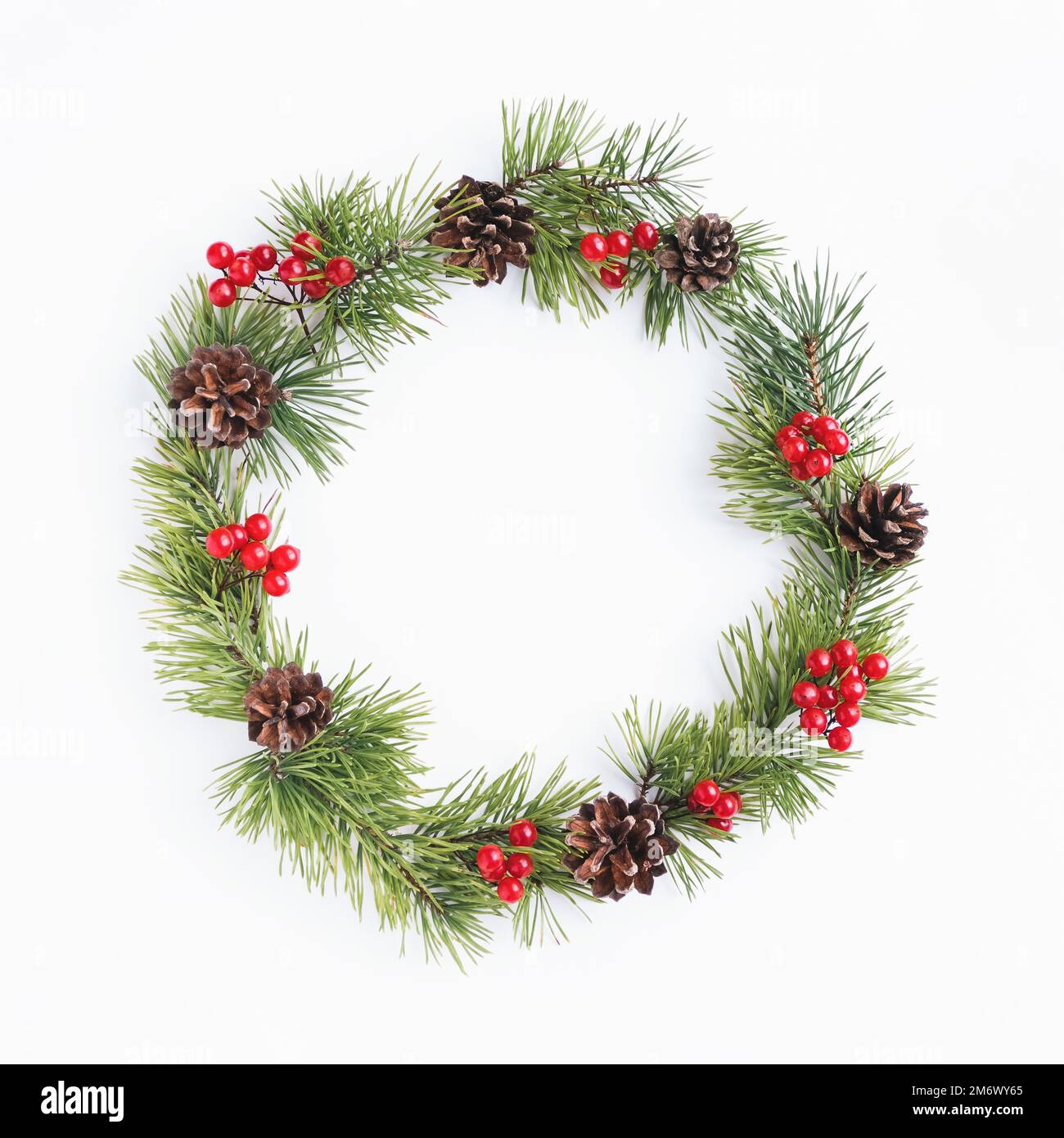 Pine christmas wreath decorated with cones and red berry fruits on white background Stock Photo