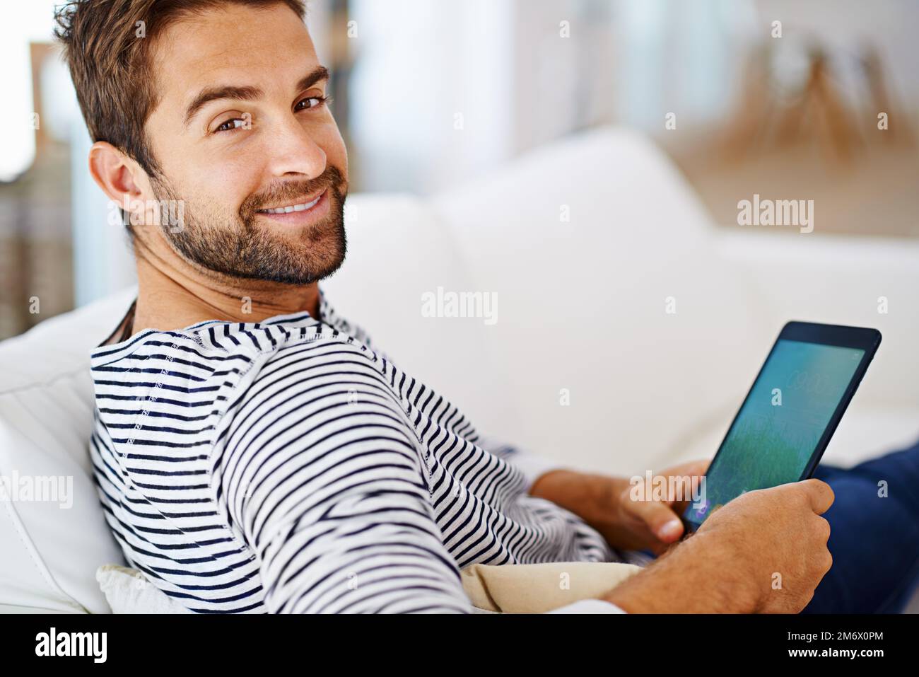 Guy Using Tablet Im up to date with my tech. Man using his tablet on his couch Stock ...